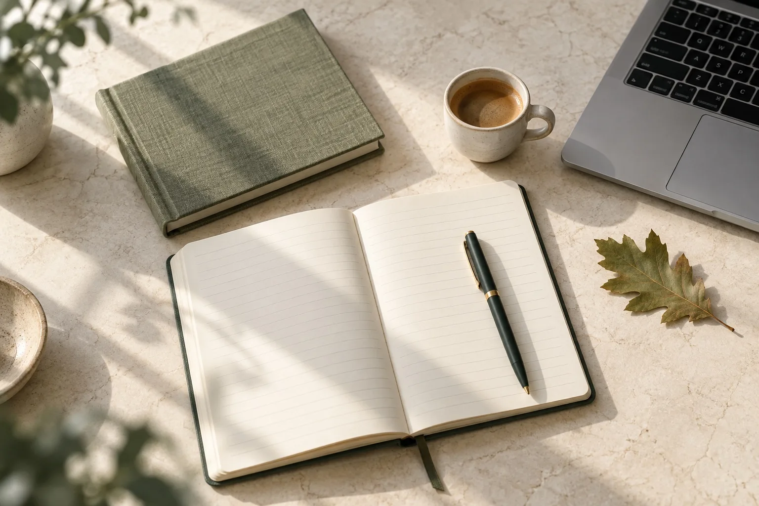 Open notebook, green pen and coffee on a sunlit desk